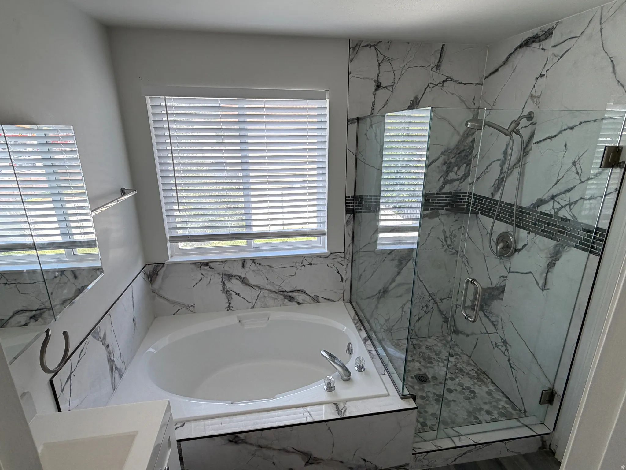 Built-in soaking tub with surround, walk-in shower with glass enclosure, white and gray veined tile, and mosaic tile shower floor