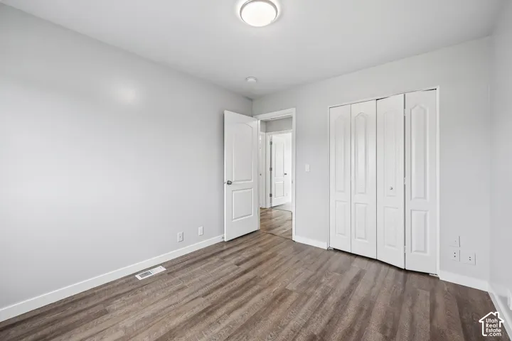 Wood-finish flooring, neutral wall paint, white trim, bi-fold closet doors, and recessed ceiling light