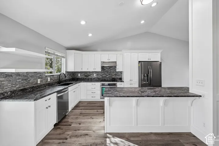 Kitchen featuring white cabinetry, dark stone countertops, a tile backsplash, wood-finish flooring, and recessed lighting