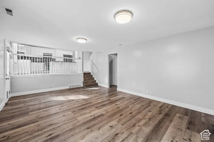Spacious living area with wood-finish flooring, white walls, and recessed lighting
