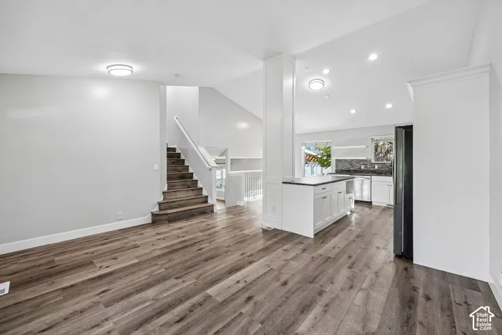 Wood-finish flooring throughout, white walls, and a staircase with wood treads