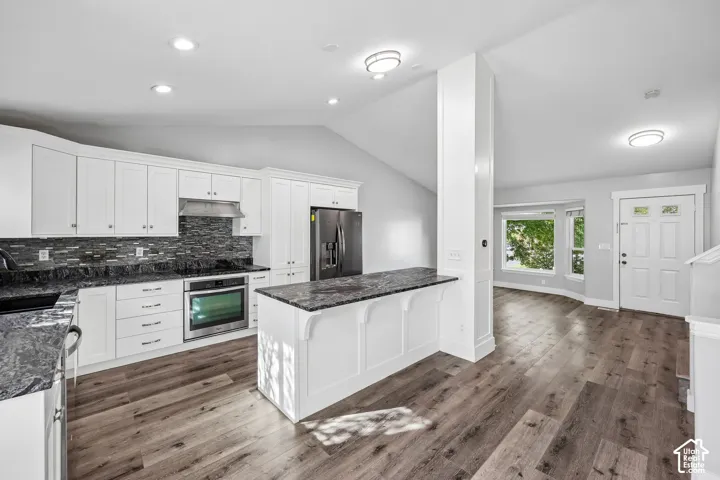 Kitchen featuring white cabinetry, dark stone countertops, tile backsplash, and stainless steel appliances