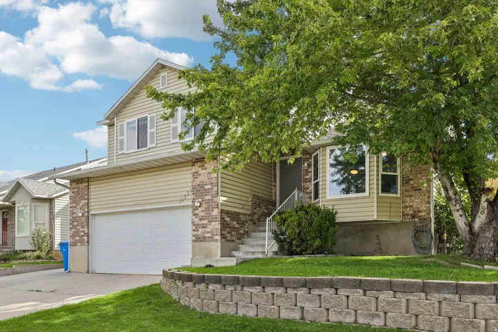 Two-story exterior with siding and brick accents, an integrated garage, a bay window, and a retaining wall