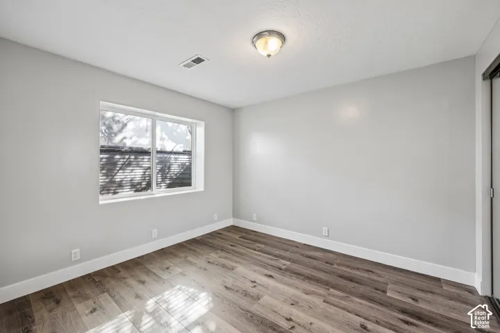 Expansive room featuring wood-finish flooring, a large window, a ceiling-mounted light fixture, and a built-in closet with sliding doors