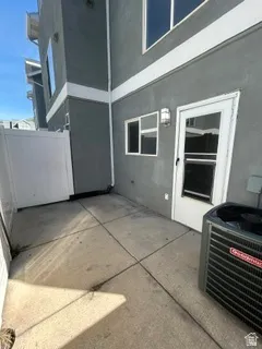Concrete patio with a white privacy fence and exterior lighting