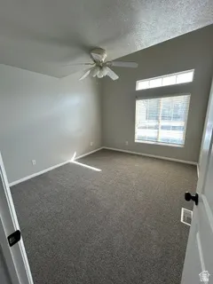 Vaulted ceiling with ceiling fan, wall-to-wall carpeting, and transom window with blinds