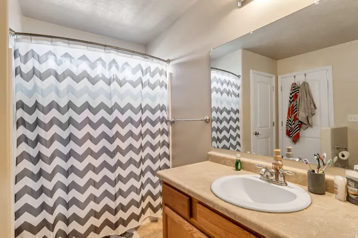 Bathroom featuring a vanity with an integrated sink, broad mirror, and overhead lighting
