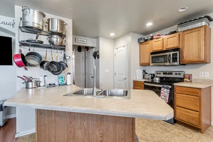 Kitchen island with a double basin stainless steel sink, wood-finish cabinetry, and stainless steel appliances