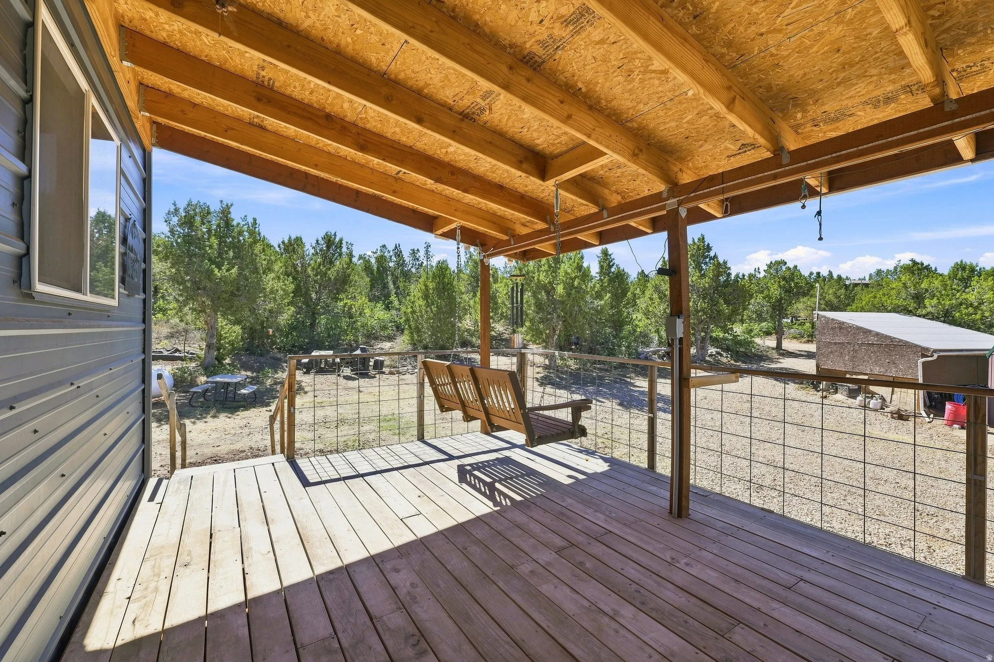 Covered wood-finish porch with a suspended bench swing