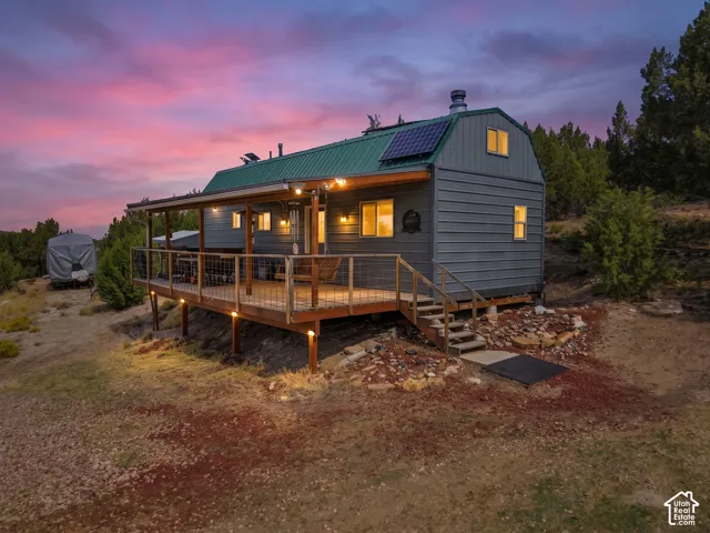 Property featuring a covered deck with string lights, solar panels, a metal roof, and durable siding