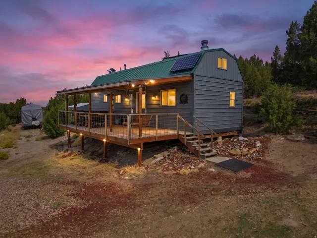Property featuring a covered deck with string lights, solar panels, a metal roof, and durable siding