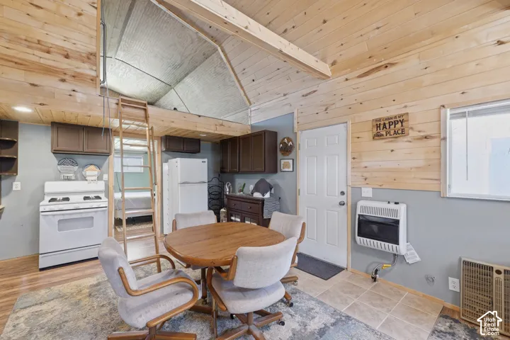 Wood-paneled walls and ceilings, wood-finish flooring, white appliances, built-in cabinetry, and a loft space with ladder access