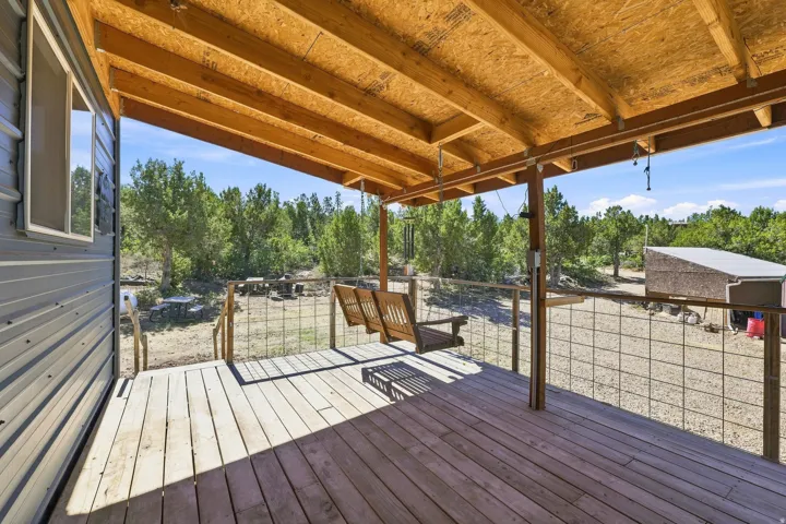 Covered wood-finish porch with a suspended bench swing