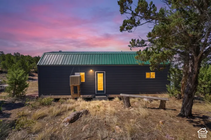 Dark siding exterior with a green metal roof and an outdoor bench