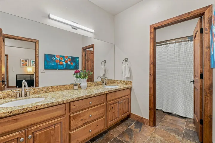 Expansive vanity featuring dual undermount sinks, a stone-finish countertop, and wood-finish cabinetry