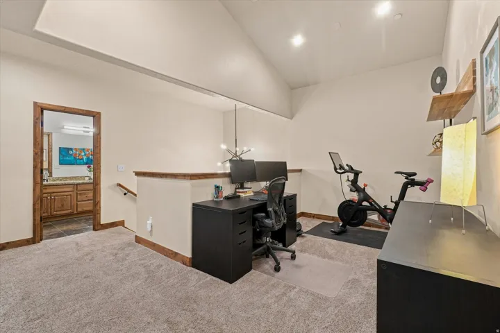Carpeted loft area featuring a vaulted ceiling and recessed lighting