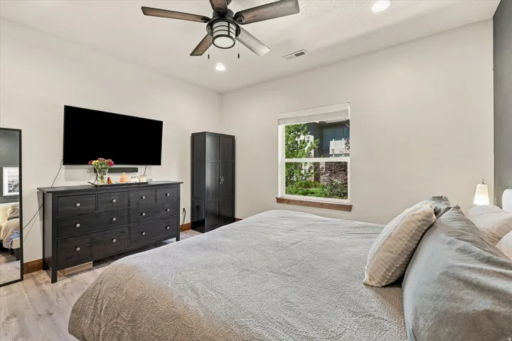 Recessed lighting, ceiling fan with integrated light, wood-finish flooring, and a window with a wood sill