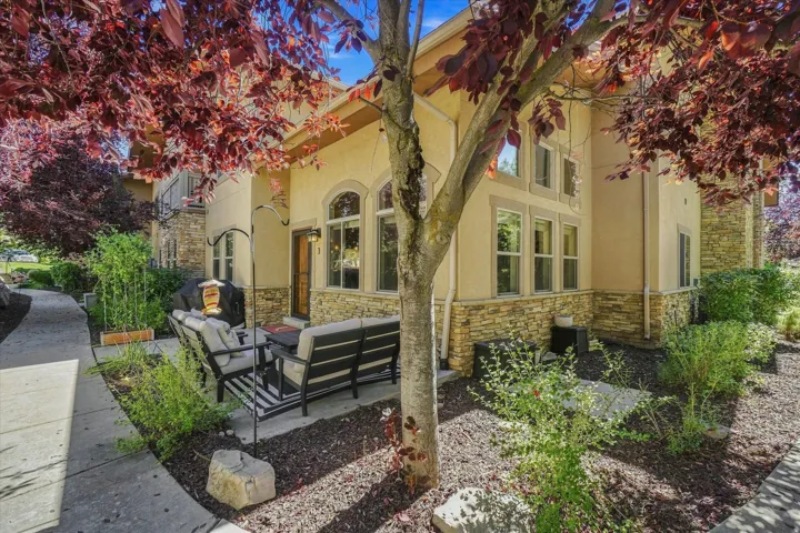 Stucco exterior with stone veneer accents, multiple arched windows, and a paved walkway