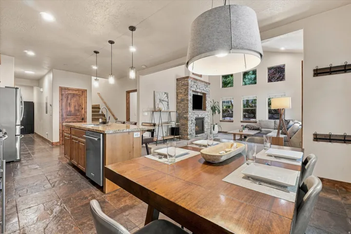 Open-concept living space with vaulted ceilings, a stone-clad fireplace, and a kitchen island featuring a sink