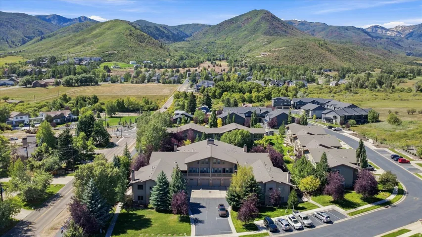 Expansive mountain scenery, residential buildings with gabled roofs, mature trees, and paved roads