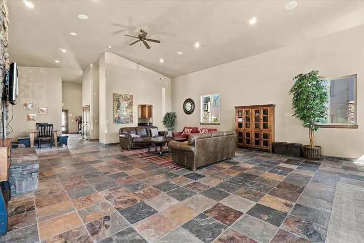 Spacious common area featuring vaulted ceilings, recessed lighting, a ceiling fan, and large format multi-toned tile flooring