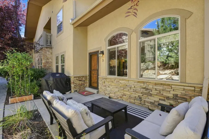Paved patio area with stone veneer accent wall, arched windows, and a wood-finish front door