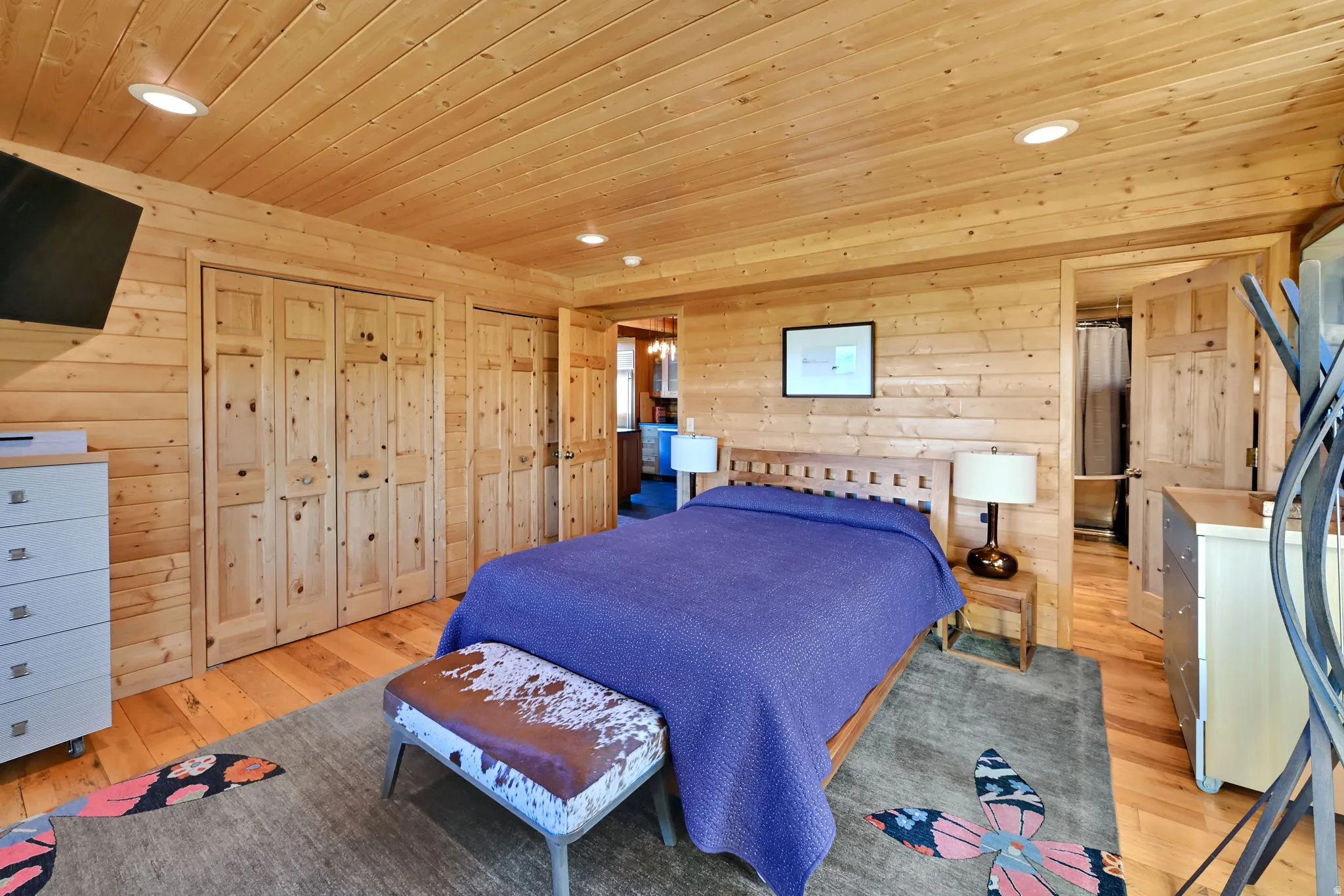 Horizontal wood paneling throughout, wood-finish flooring, two sets of bifold wood doors, and recessed ceiling lighting