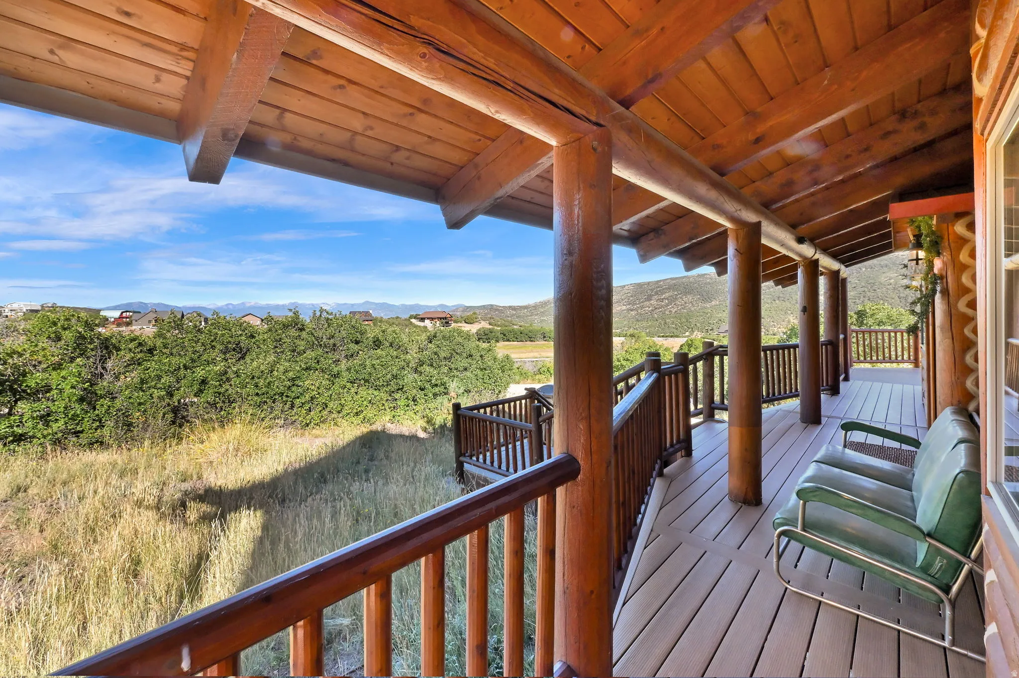 Covered deck featuring wood-finish ceiling, exposed log beams, and a composite deck surface