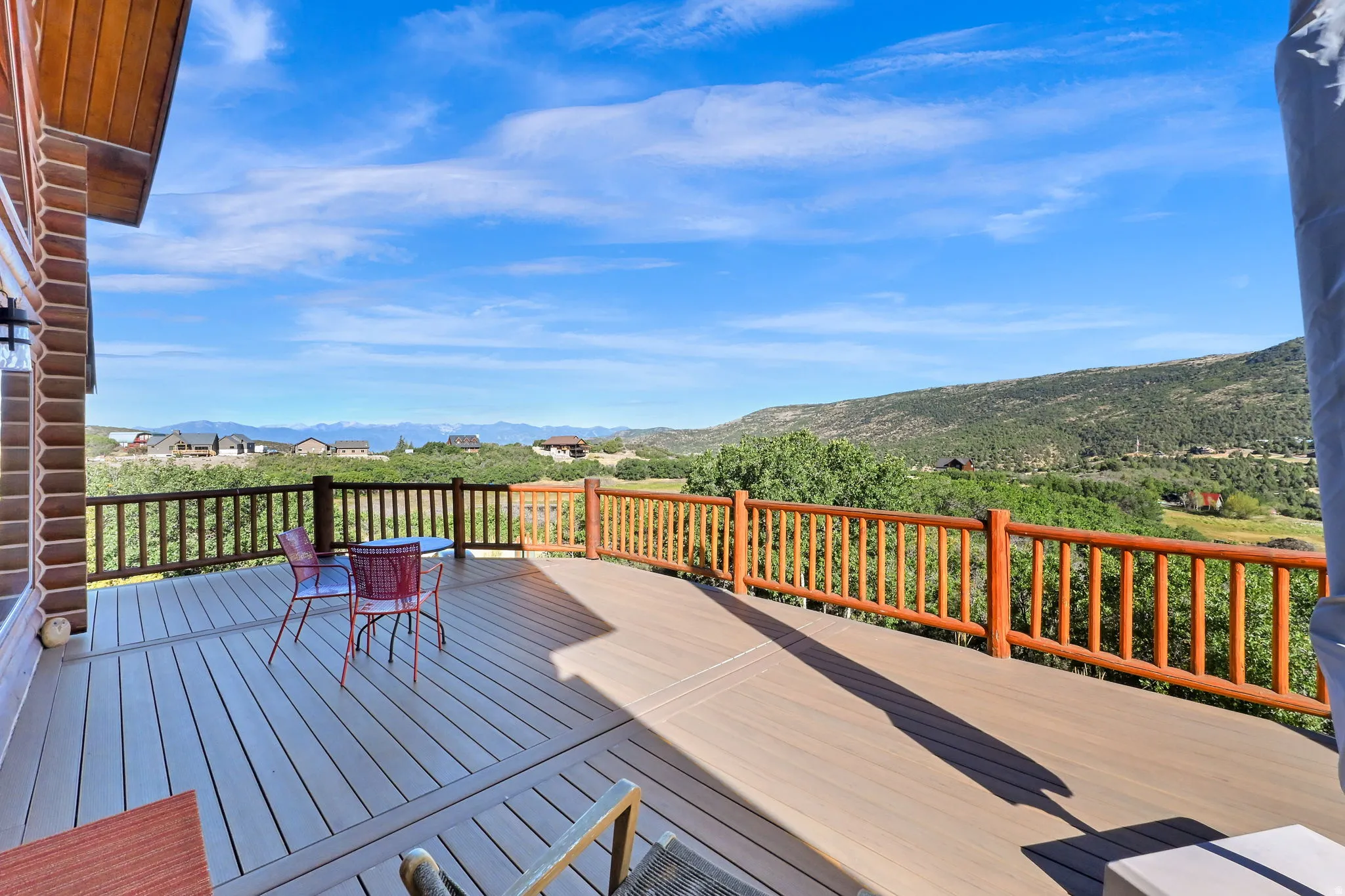 Expansive outdoor deck with composite decking, rustic log railing, and a log-sided exterior