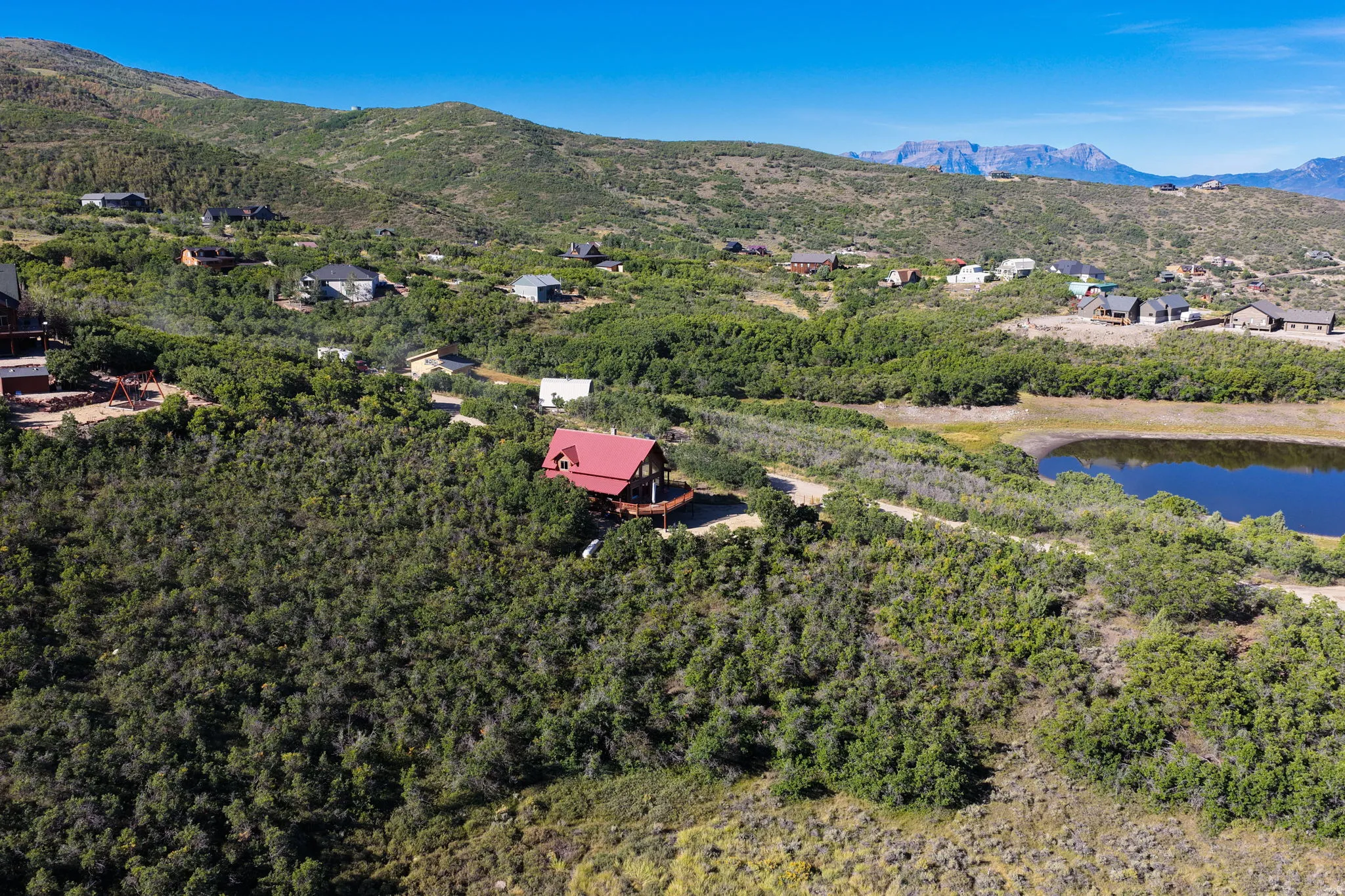 Mountain terrain, residential structures, scattered vegetation, body of water, clear sky