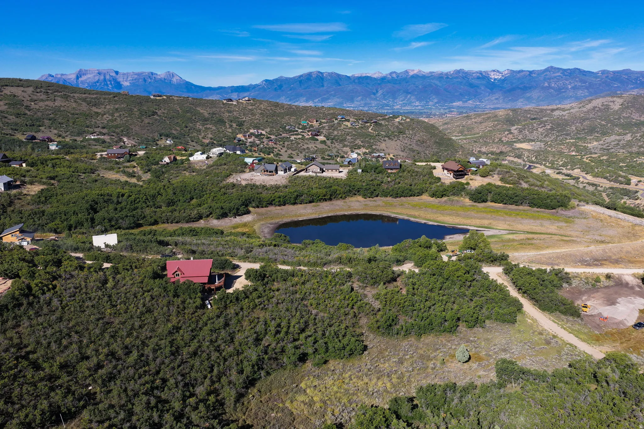 Expansive property featuring a private pond, surrounding natural foliage, and mountainous terrain