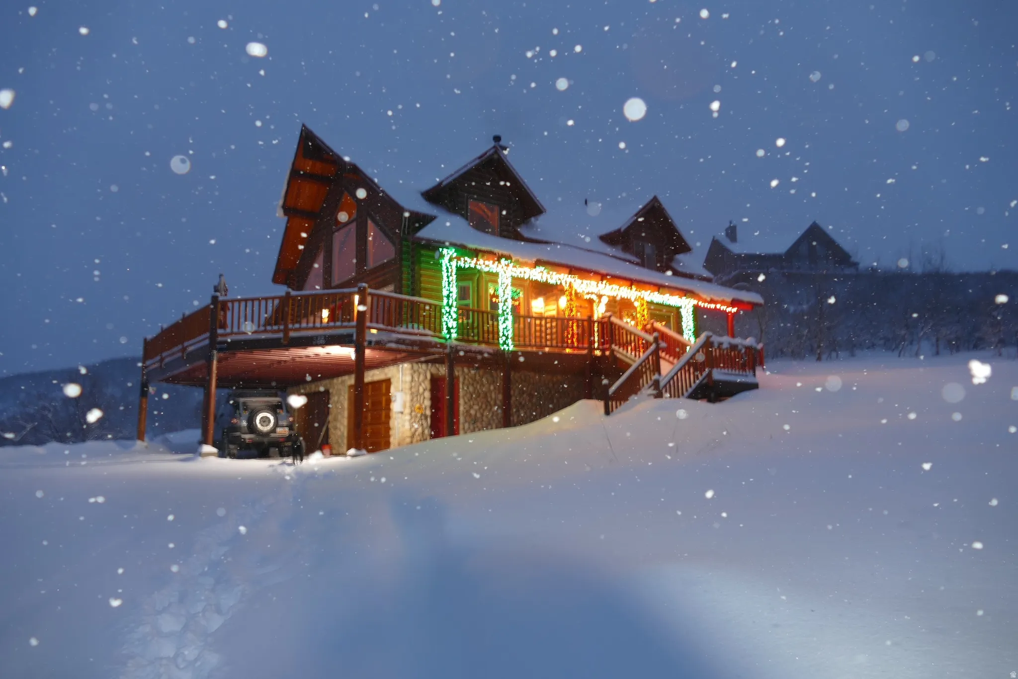 Exterior featuring log siding, stone foundation, multi-level decking, and a covered porch