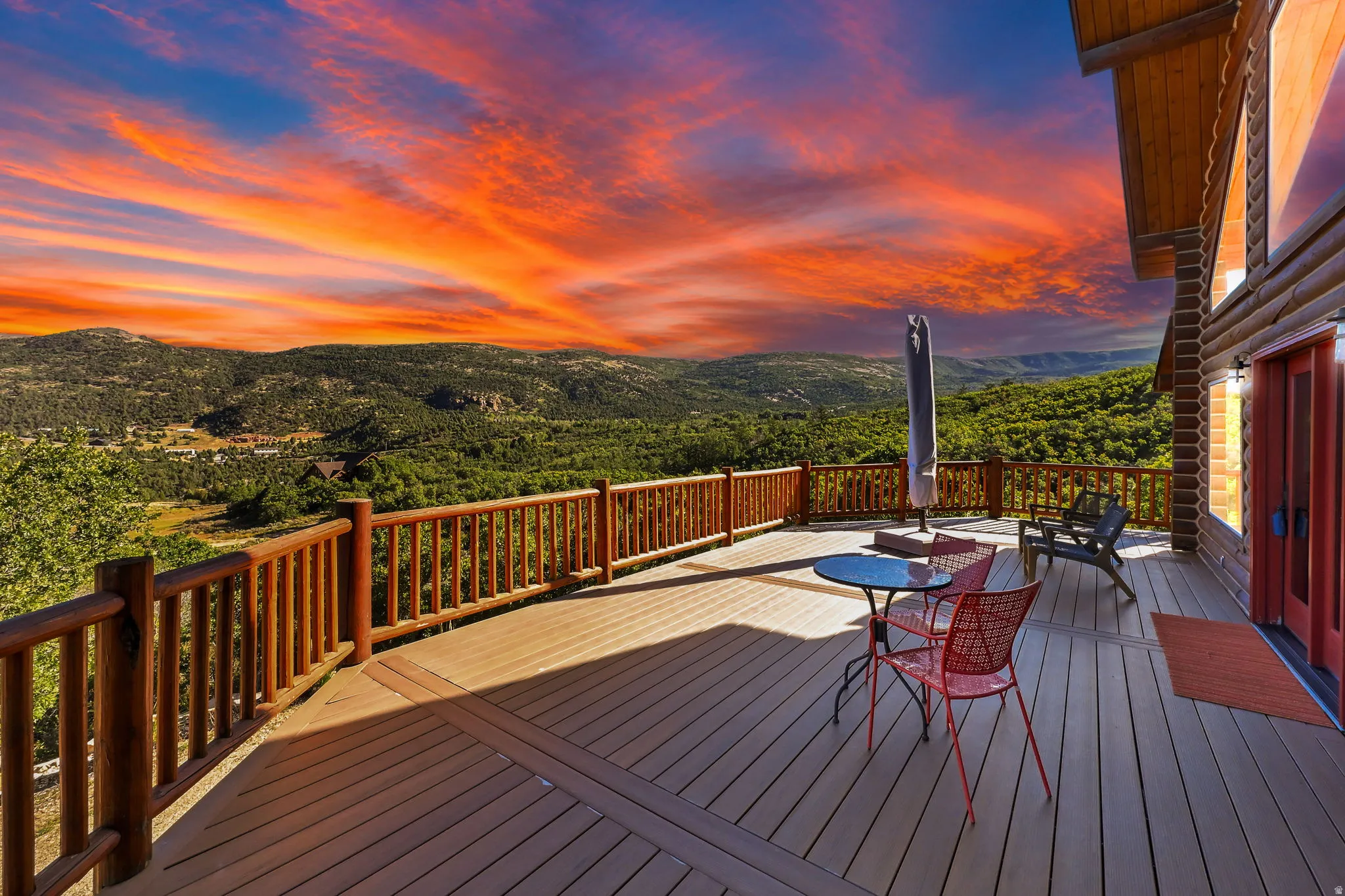 Expansive outdoor deck with wood-finish flooring, natural wood railing, and mountain scenery