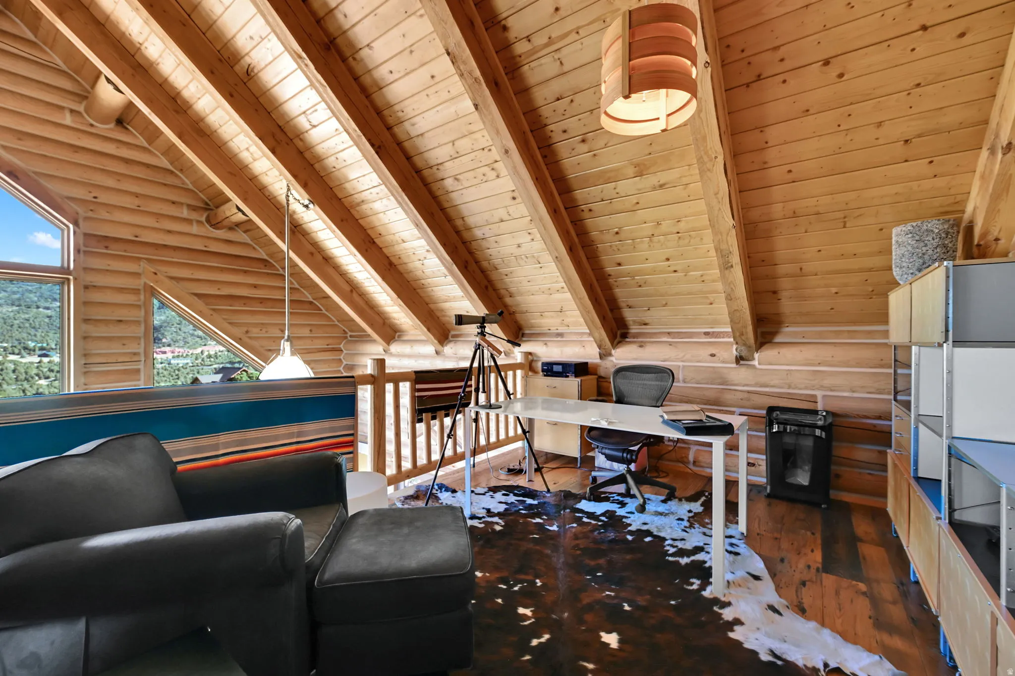 Angled wood-paneled ceilings with exposed beams, wood-finish flooring, and built-in shelving