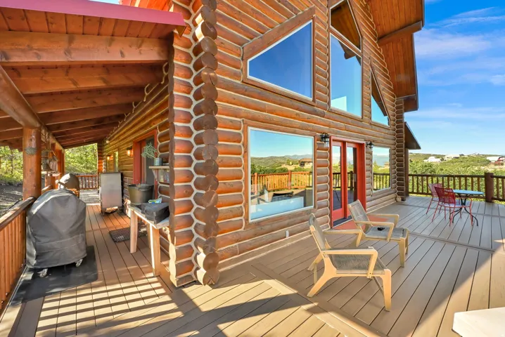Log home exterior with a multi-level deck, expansive windows, and a covered patio area