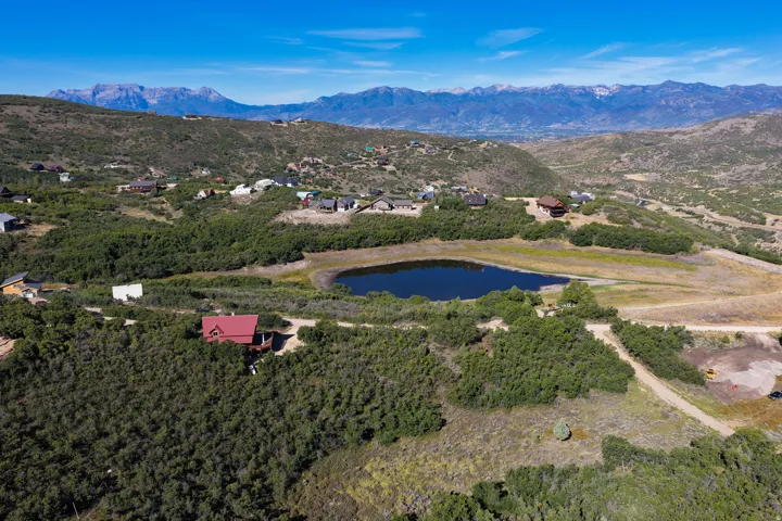 Expansive property featuring a private pond, surrounding natural foliage, and mountainous terrain