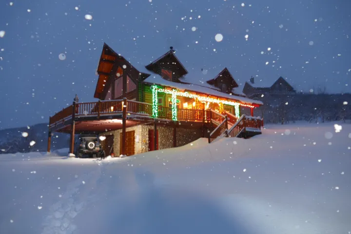 Exterior featuring log siding, stone foundation, multi-level decking, and a covered porch