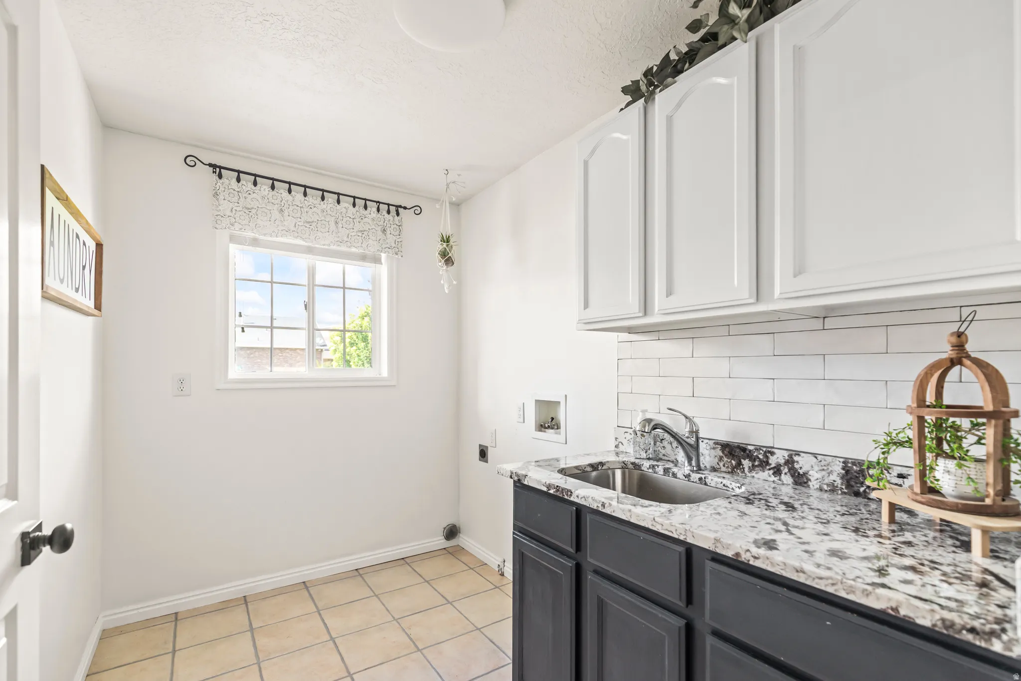 Built-in cabinetry with a utility sink, polished chrome faucet, stone countertop, and tile backsplash