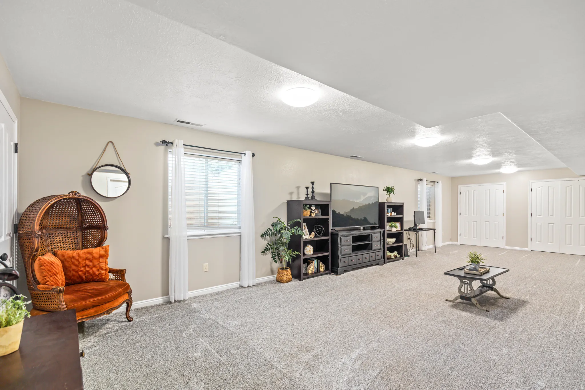Spacious room featuring neutral carpeting and wall tones, recessed lighting, and a window with horizontal blinds