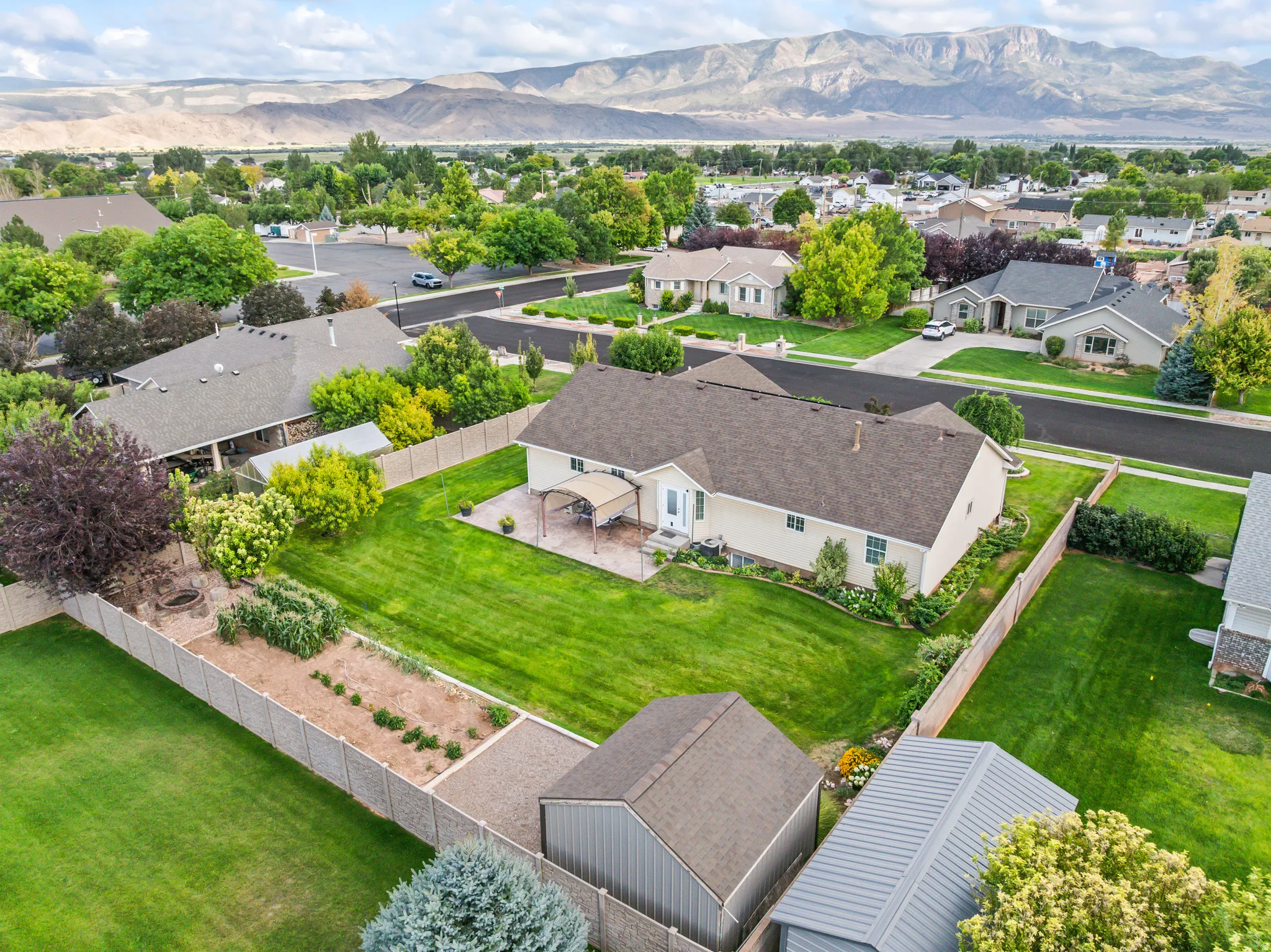 Expansive backyard with a manicured lawn, established garden beds, and mature landscaping