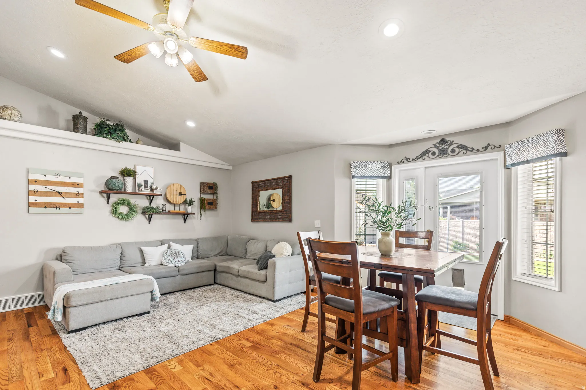 Vaulted ceiling with recessed lighting, wood-finish flooring, ceiling fan, and a built-in display ledge