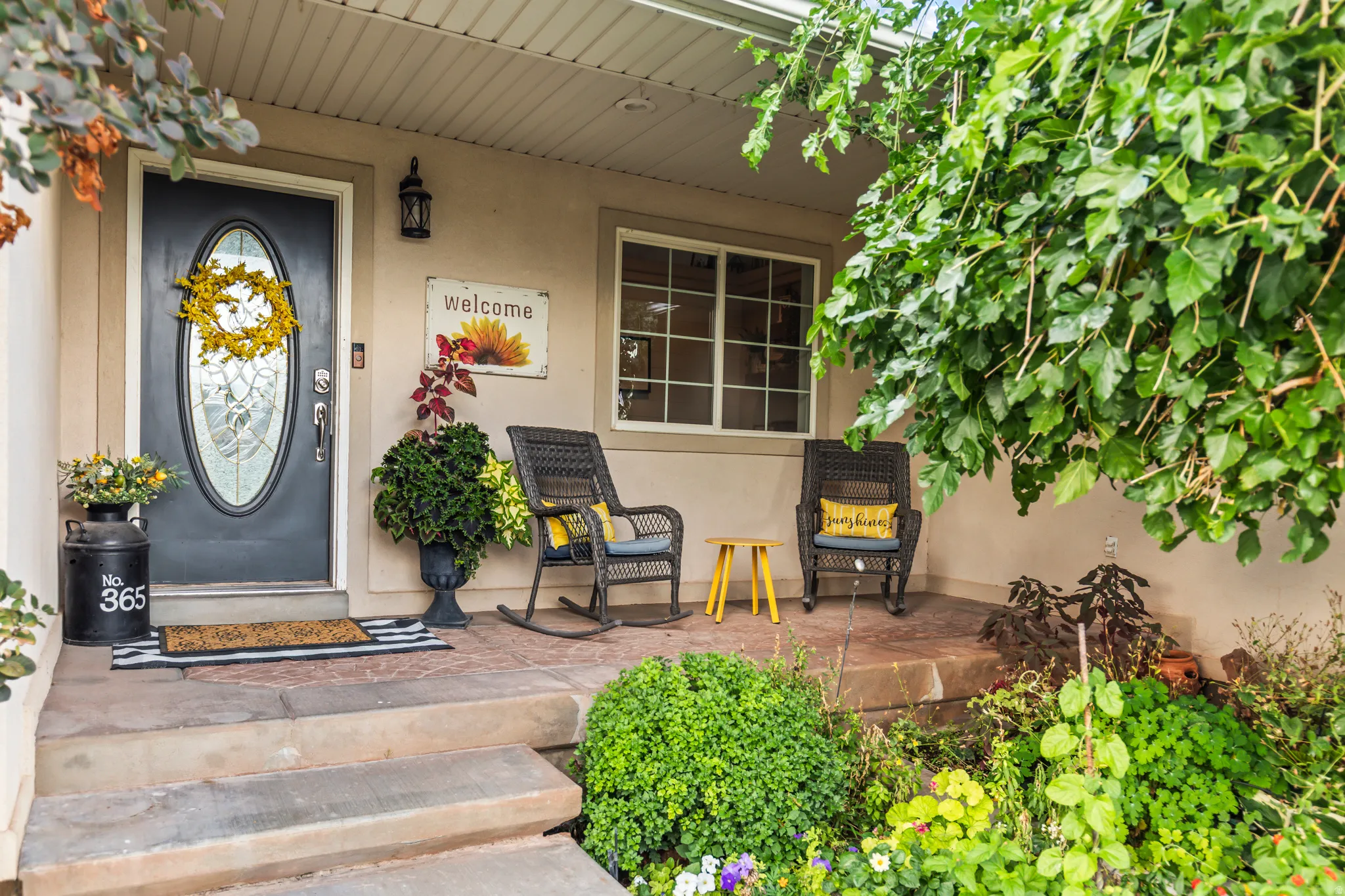 Inviting covered porch with a paneled entry door featuring an oval glass insert, a single window with grids, and concrete steps