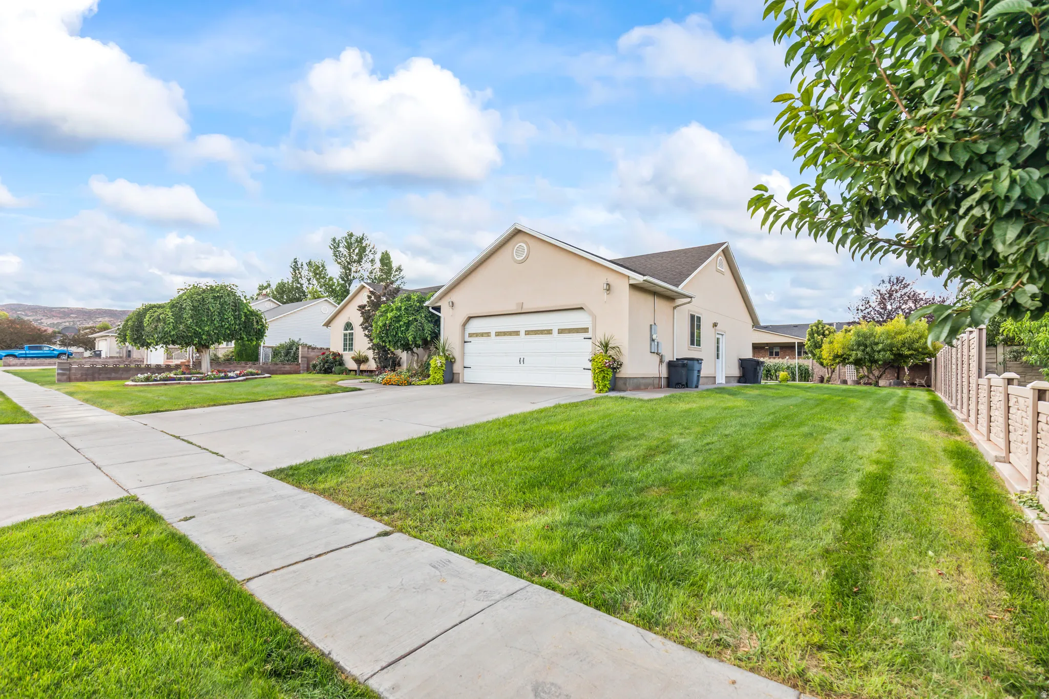 Stucco exterior with a two-car garage, concrete driveway, and a fenced yard