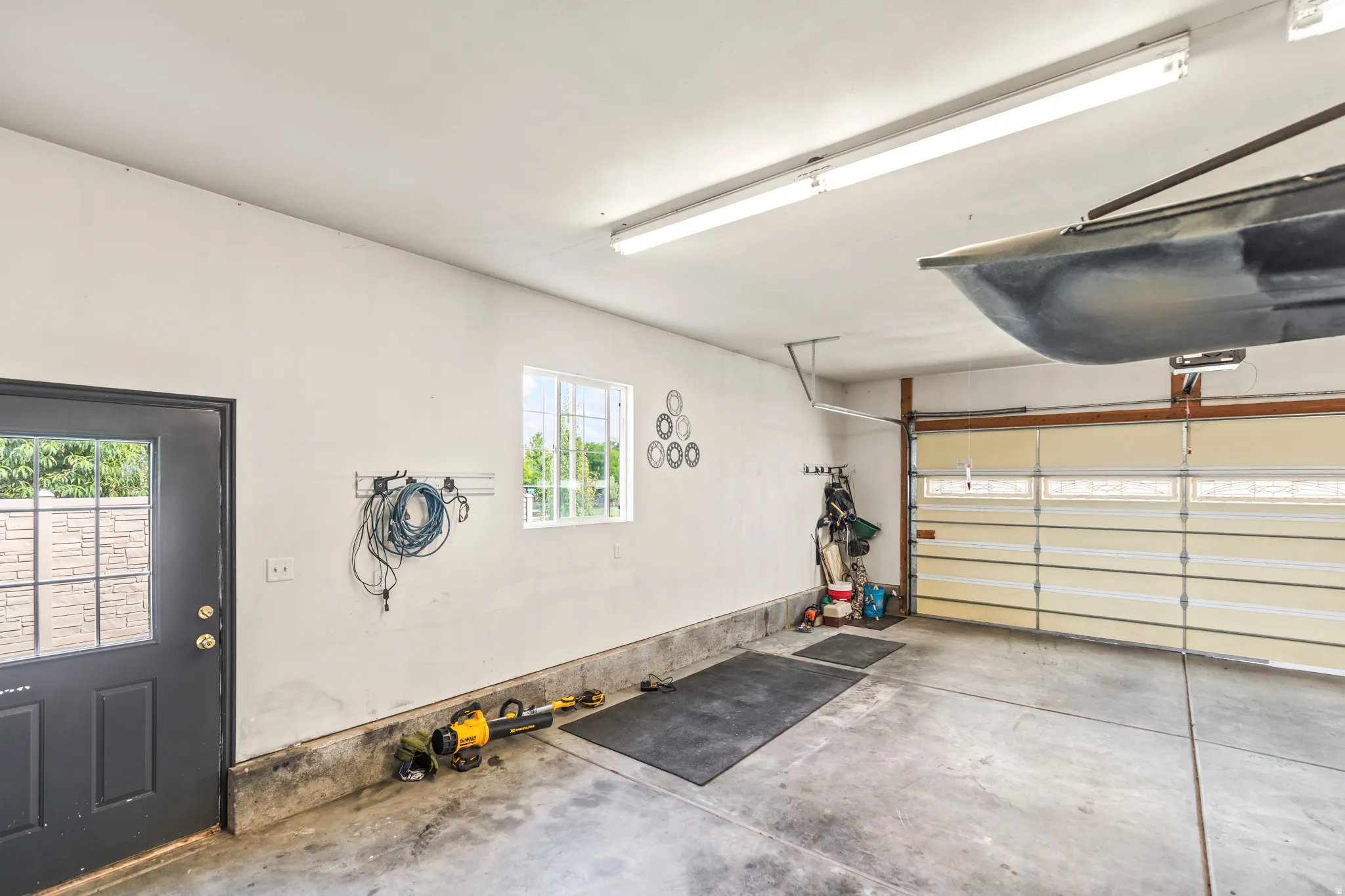 Spacious garage with a concrete floor, overhead fluorescent lighting, a window, and a paneled garage door