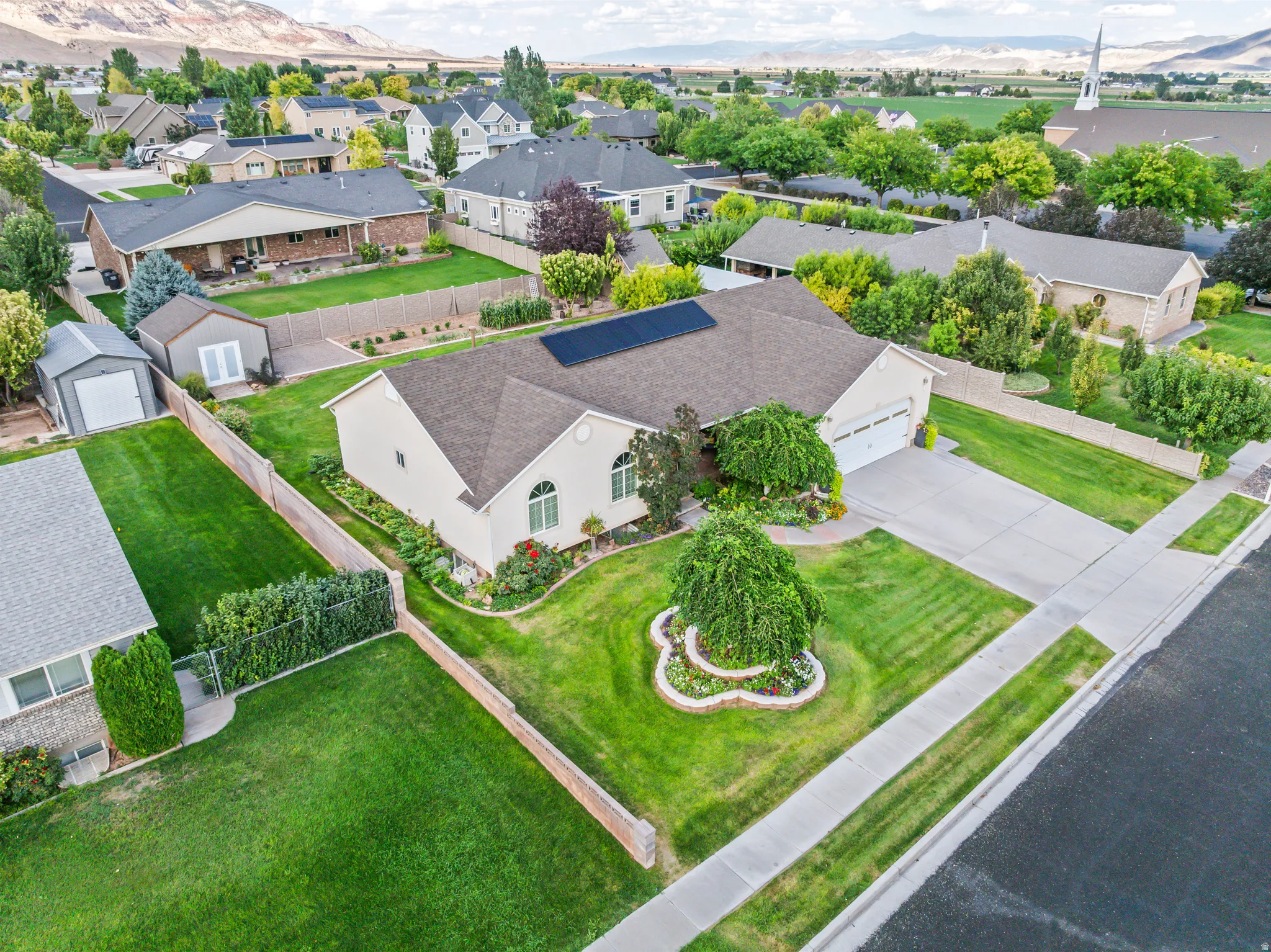 Well-maintained exterior with a paved driveway, mature landscaping, and a fenced yard
