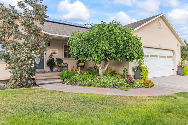 Stucco exterior with a two-car garage, mature landscaping, and solar panels