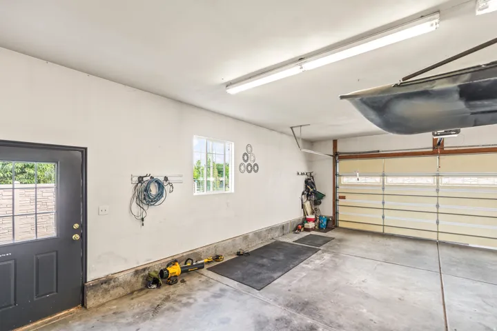 Spacious garage with a concrete floor, overhead fluorescent lighting, a window, and a paneled garage door