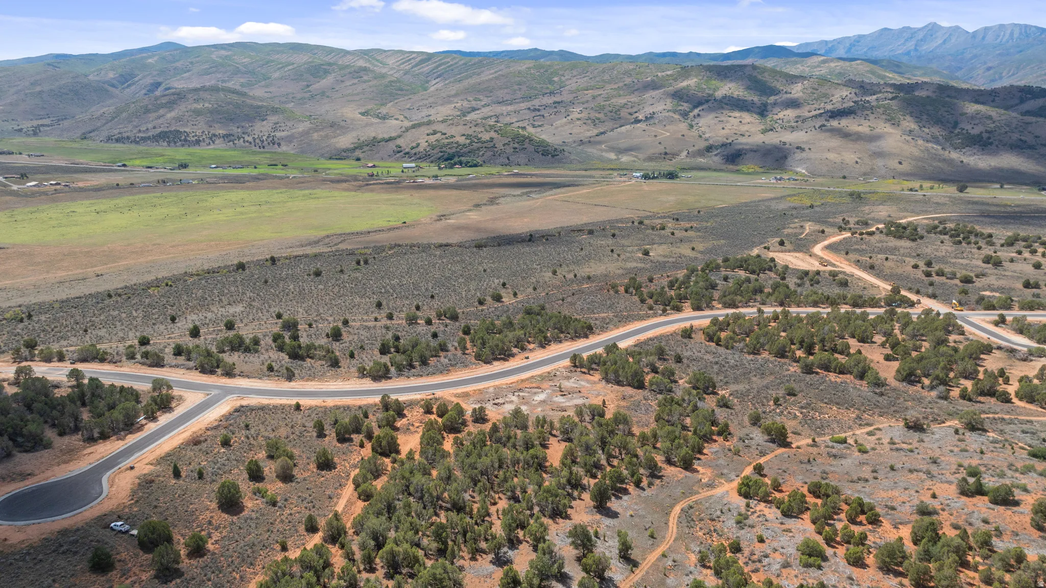 Paved roads winding through a landscape with scattered trees, expansive open land, and distant mountains