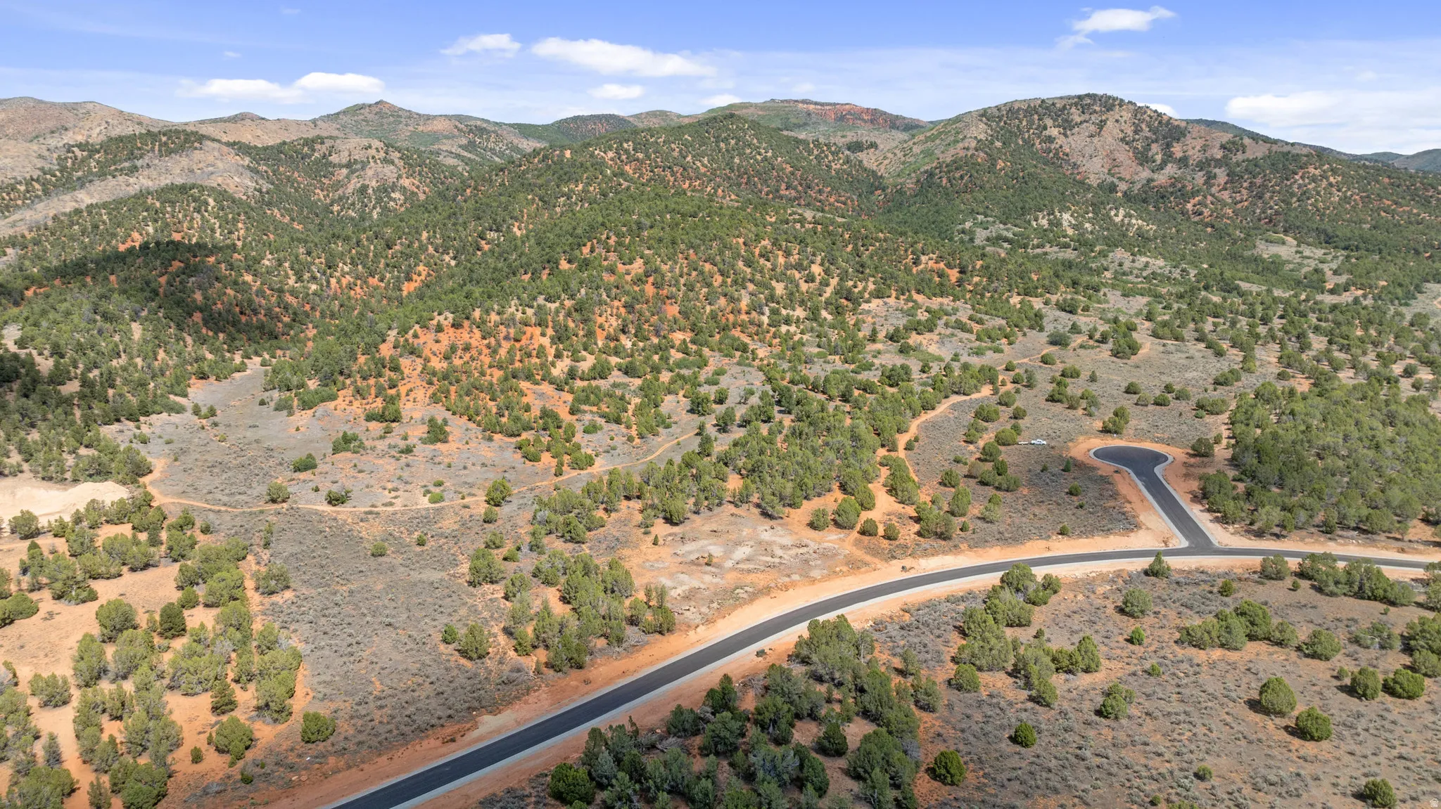 Sweeping landscape with mountainous terrain, abundant natural foliage, and a paved road
