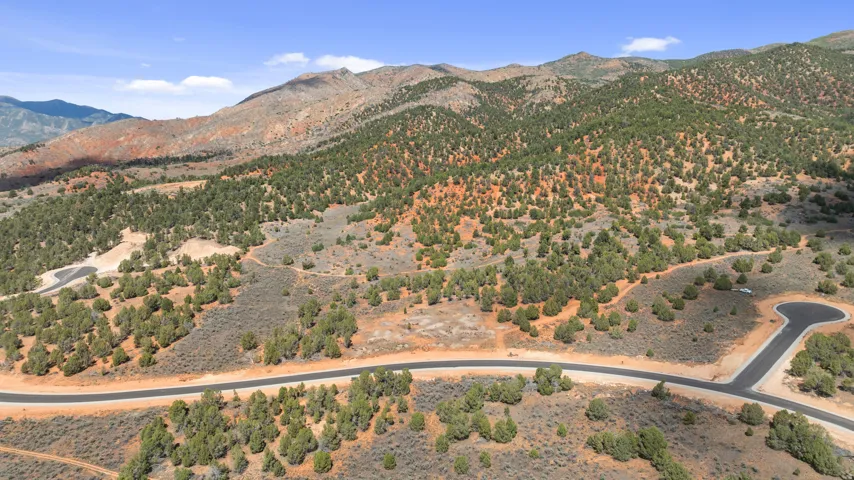 Mountainous terrain with natural vegetation, asphalt road, and cul-de-sac